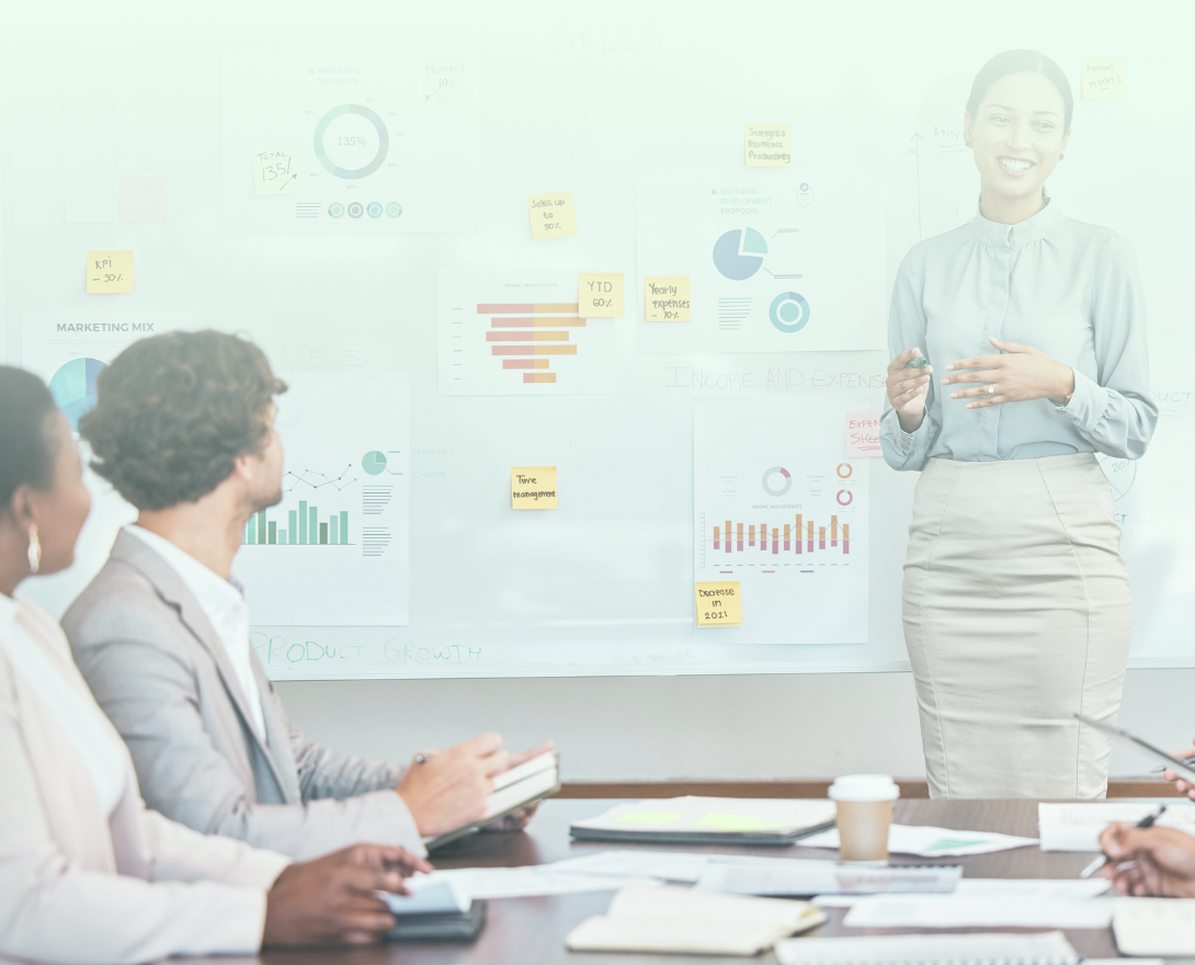 A human resource director, a woman in a blue blouse and khaki skirt, is standing in front of a board full of data presenting pipeline data aggregated from the Torace Premium plan to hear team as they sit at a conference table. A human resource director, a woman in a blue blouse and khaki skirt, is standing in front of a board full of data presenting pipeline data aggregated from the Torace Premium plan to hear team as they sit at a conference table.